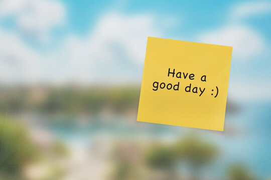 Have a good day written on a post-it with a blurry city view in the background