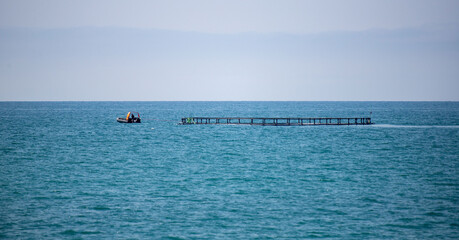 A boat is floating in the ocean near a pier