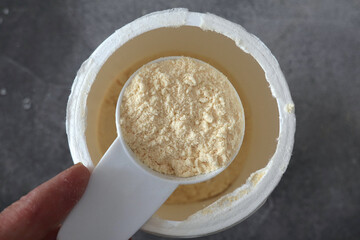 Top view of a scoop of colostrum powder above an open container