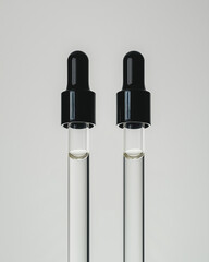 Fototapeta premium Closeup of two black droppers filled with cosmetic oil background