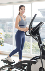 Asian young beautiful cheerful happy woman active girl in sportswear stationary exercise bike...