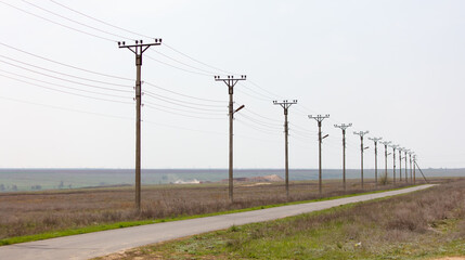 A long line of power poles are in a field
