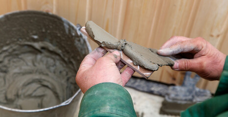 A man is holding a piece of tile in his hand while working with cement