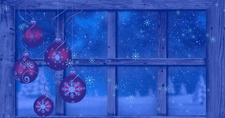 Image of snow falling over christmas baubles decoration and winter scenery