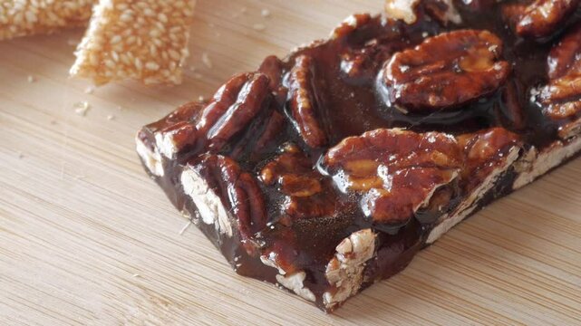 Zoom out view of nougat and sesame bar with honey. Traditional spanish Guirlaches.