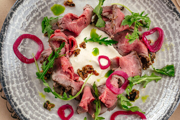beef tenderloin with sauce, onion and arugula