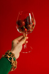 Holiday-themed raised hand with a glass against red background