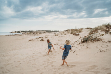 Children running having fun in sand dunes beach cloudy day © Cavan