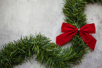 red bow on green garland on a gray background with copy space