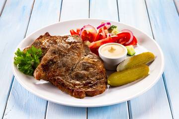 Roasted chuck steak with mayonnaise and fresh vegetables on wooden table
