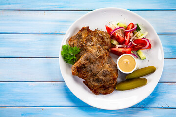 Roasted chuck steak with mayonnaise and fresh vegetables on wooden table