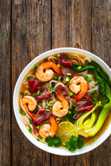 Shrimp and beef Pho soup - Vietnamese soup with shrimps and raw beef slices on wooden table	
