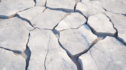 Obraz premium Dry cracked earth showcases the impact of drought in a parched landscape under a clear blue sky