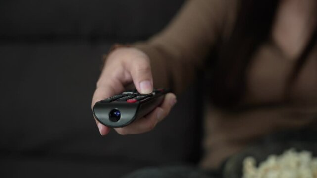 Woman Watching smart TV and using remote controller Hand holding popcorn at home