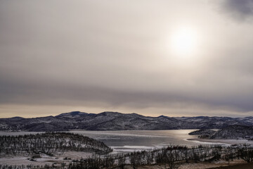 Winter landscape of frozen Baikal with ice and mountains under a cloudy sky