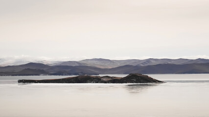 Winter landscape of Baikal with icy waters and distant mountains under a gray sky