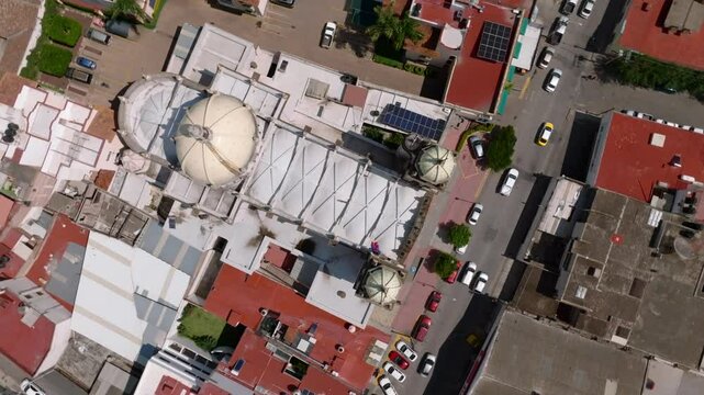 Aerial top down of San Pedro Church and traffic on street during sunny day. Ciudad Guzman Tuxpan Jalisco. Circling rising shot.