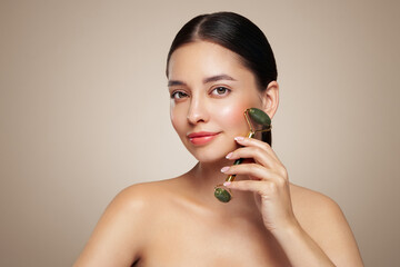 Close up video of a young woman looking relaxed and smiling while using a natural jade face roller....