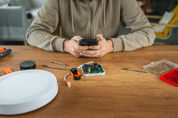 Person repairing smart phone with tools on a wooden table
