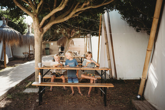 Young kids crafting at campsite with teepees in summer