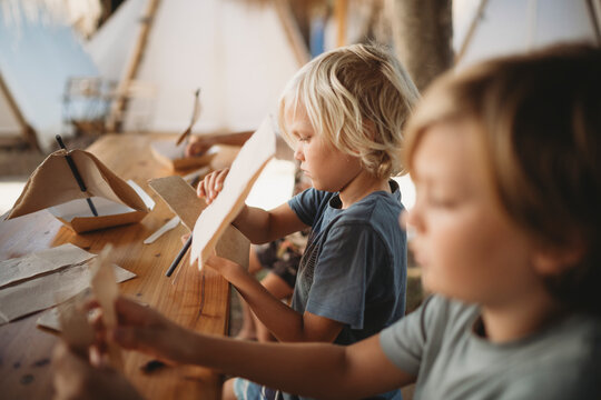 Young kids making crafts at campsite in summer