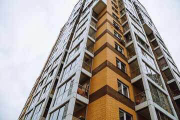 Modern residential building in Irkutsk with striking red accents against a cloudy sky