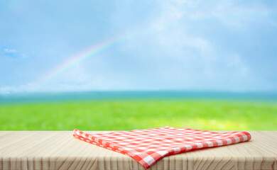 Fabric cloth or placemat on wood table top on fresh blue sky with rainbow