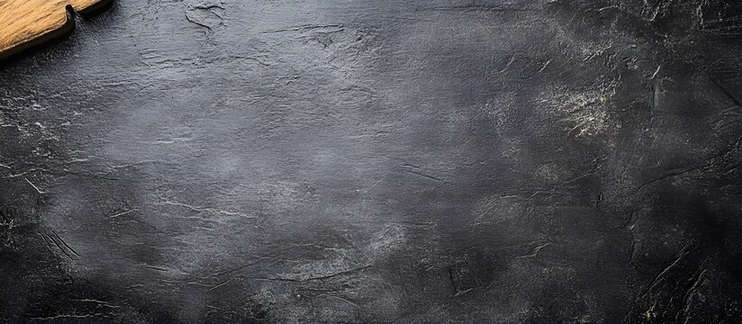 Dark rustic stone texture background with wooden cutting board corner.