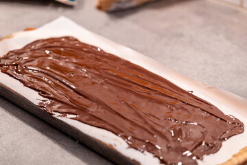 Stockholm, Sweden Melted chocolate is spread onto wax paper to add nuts and raisins to make chocolate candies.