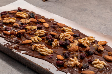 Stockholm, Sweden Melted chocolate on wax paper with nuts and raisins to make chocolate candies.