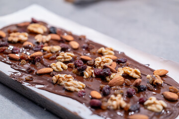 Stockholm, Sweden Melted chocolate on wax paper with nuts and raisins to make chocolate candies.