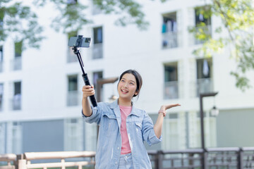 Asian female influencer online recording her lifestyle to her followers at outdoor.