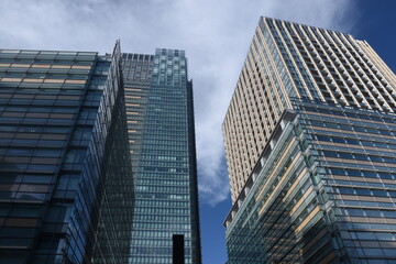 Obraz premium Modern skyscrapers with glass and beige facades rise against a deep blue sky in Roppongi, Tokyo.