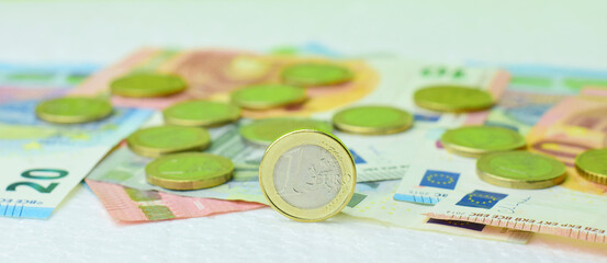 Close up. Scattered euro coins and bills, of different amounts, on a light background.