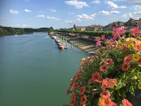 vue sur la Sa&ocirc;ne , la rivi&egrave;re qui passe &agrave; Tournus en Bourgogne, le pont est orn&eacute; de fleurs avec un ciel bleu et quelques nuages 