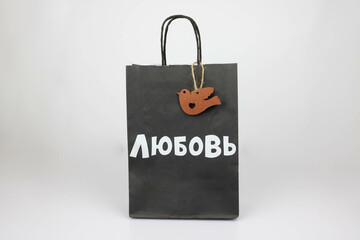 A black paper bag with a wooden bird and the word Love in white Russian letters. The concept of...