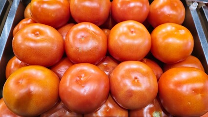 Tomatoes stacked on the counter for sale. Large colored product.