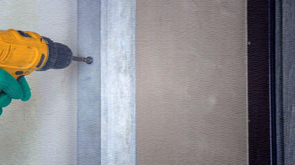 Person is using a drill to make a hole in a wall