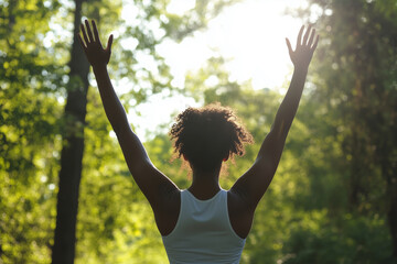 woman is standing in a forest, with her arms raised in the air. Concept of freedom and joy, as the woman is celebrating or expressing her happiness