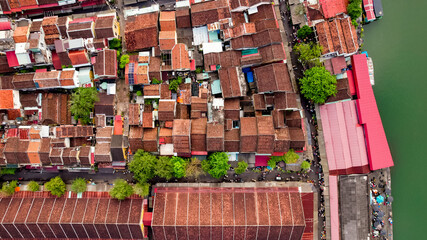 Aerial view of densely packed red-roofed buildings in an Indonesian city evokes urban overcrowding,...