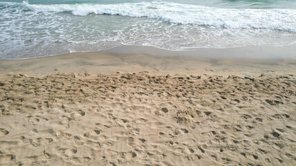 Sandy beach with ocean waves symbolizes summer vacations and relaxation, perfect for promoting coastal travel and leisure concepts