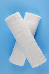 Gauze medical bandage on a blue background. Cross made from rolls of bandage on a blue background.