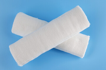 Gauze medical bandage on a blue background. Cross made from rolls of bandage on a blue background.