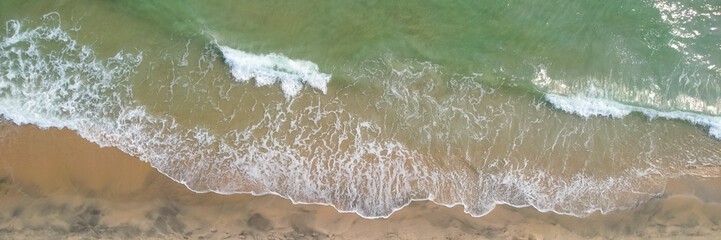 Aerial view of ocean waves gently crashing onto a sandy beach, evoking relaxation and perfect for...
