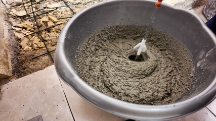 A close-up of cement mixing in a bowl symbolizing construction and home renovation challenges