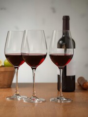 Elegant wine glasses filled with red wine, beside a bottle, festive, red wine, celebration