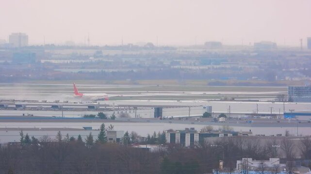 A red airplane prepares for takeoff on a cloudy day at Toronto Pearson International Airport