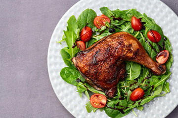 Grilled chicken legs with tomatoes and salad . Top view