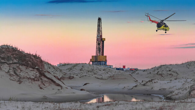 Oil and gas field in the Arctic. Summer. Sandy landscape with small lakes. Drilling rig. Flying helicopter