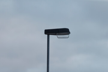 A solitary street light stands tall against a backdrop of a dramatically cloudy evening sky,...